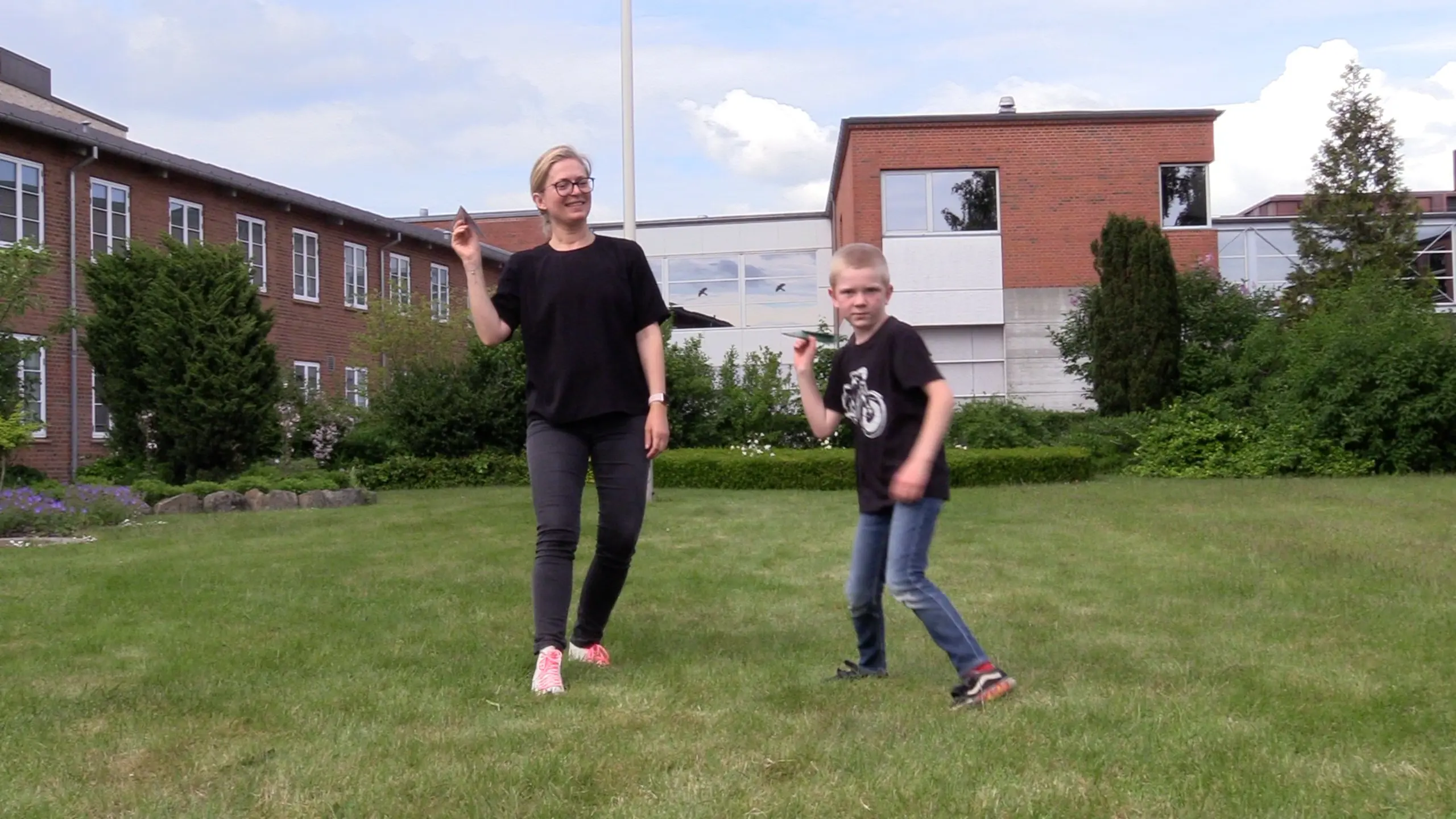 mother and son playing with paper planes in the garden